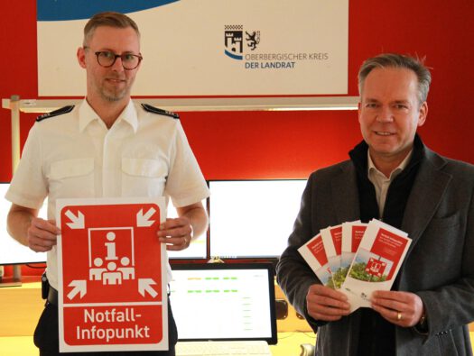 Julian Seeger (Leiter Feuer- und Rettungsleitstelle OberbergischerKreis, l.) und Kreisdirektor Klaus Grootens (r.) zeigen die Flyer und die
geplanten Hinweisschilder für die Notfall-Infopunkte. (Foto: OBK)